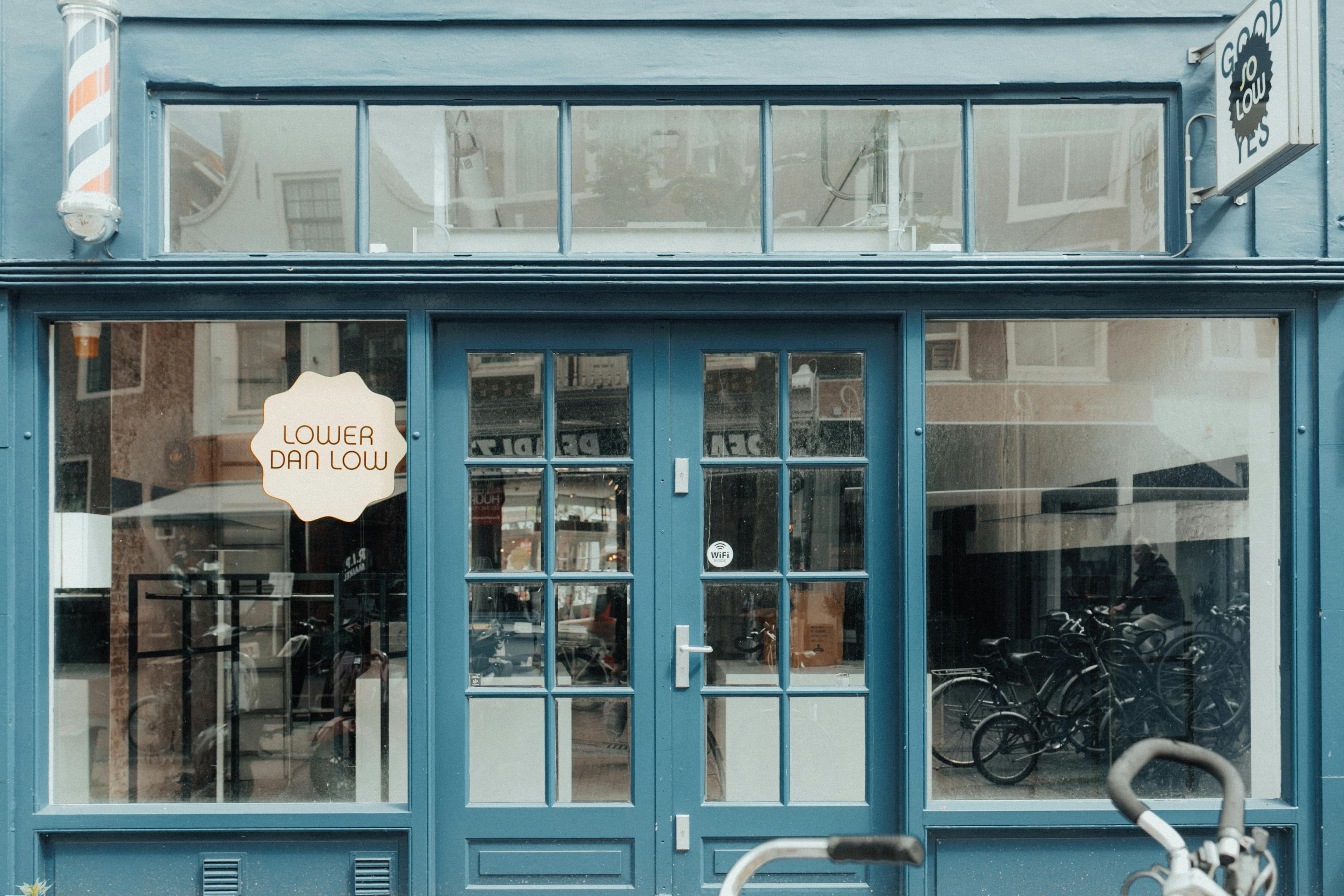 Blue storefront with large glass windows and reflections from the street outside.